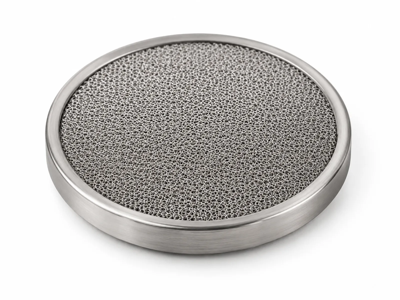 A round sintered stainless steel espresso puck screen resting on a tamped coffee puck inside a portafilter basket