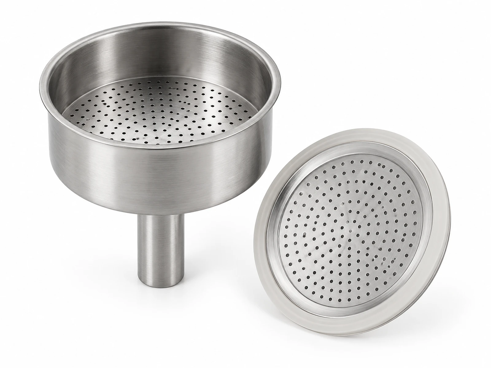 A disassembled stainless steel moka pot showing the perforated funnel basket filled with ground coffee and the filter plate